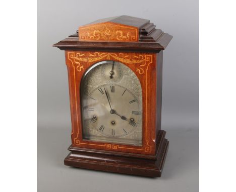 A Victorian mahogany inlaid bracket clock by Kienzle Uhren, featuring an architectural case and an arched silvered dial with 