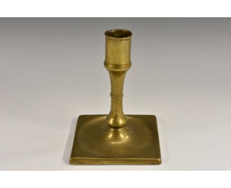 A George I/II brass candlestick, of seamed construction and short proportions, dished square base, 13.5cm high, c.1730