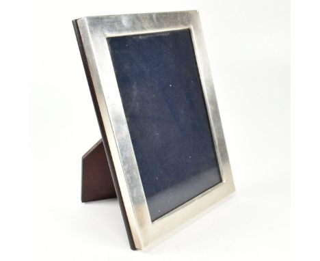 A contemporary hallmarked silver picture frame. The picture of photo frame of plain form having a hard wood easel back and gl