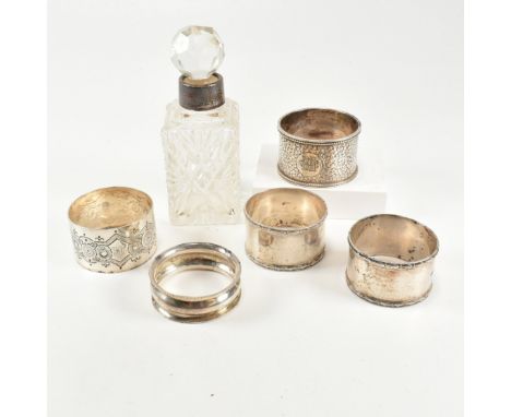 A collection of hallmarked silver napkin rings and silver collared perfume bottle. The lot to include a George V cut glass pe