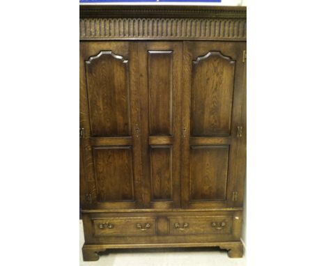 A 20th Century oak two door wardrobe with dentil carved corners above two panelled doors above two drawers, the whole to brac