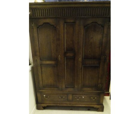 A 20th Century oak two door wardrobe with dentil carved corners above two panel doors above two drawers, the whole to bracket