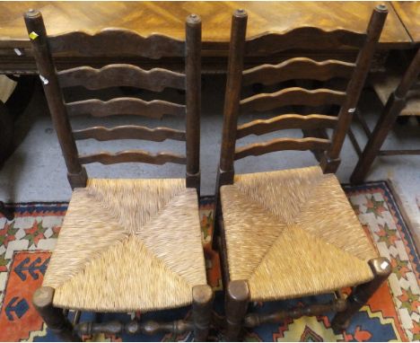 A set of ten oak ladder back rush seated dining chairs and a pine drop-leaf circular table, raised on turned and ringed legs 