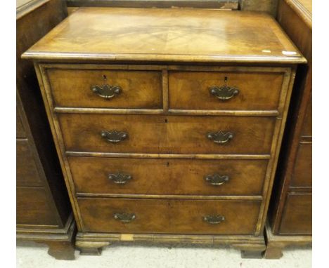 A walnut and mahogany cross banded chest of two short and three long drawers with ogee bracket feet, the whole in the Georgia