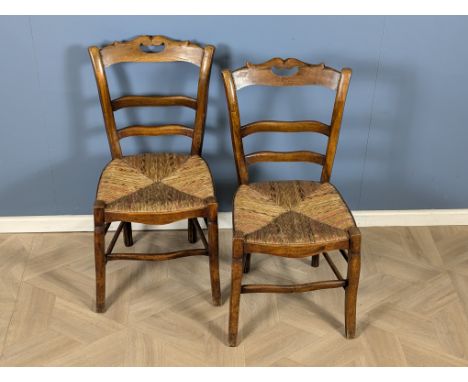 A pair of 19th century French provincial walnut ladder back side chairs with rush seats, raised upon shaped square section fr