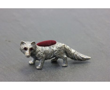 A silver fox pincushion with ruby eyes