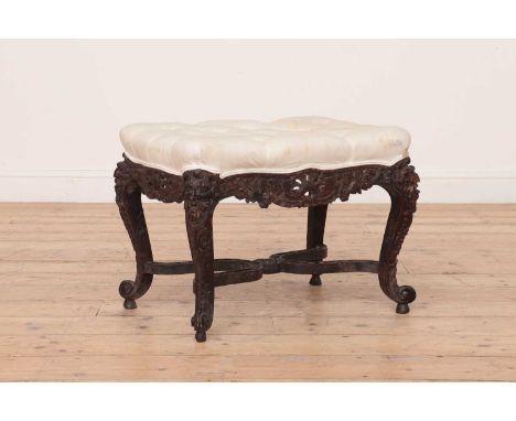 A French Regency-style carved oak stool,c.1900, with a button upholstered seat, the frame carved with a shell acanthus leaf a