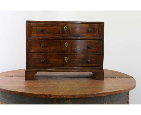A continental miniature walnut commode,mid-19th century, with a serpentine front and crossbanded decoration, on bracket feet,