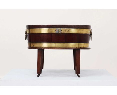 A George III mahogany and brass wine cooler,of oval shape with brass ring handles, raised on tapering supports terminating in