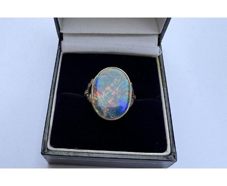 A large opal ring, the collet set opal showing a range of colours, measuring approximately 18mm across,  small diamonds to th