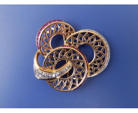 A diamond &amp; ruby set yellow metal sunflower brooch, formed as three conjoined stylised openwork flowerheads, with borders