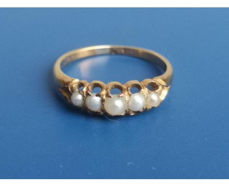 A yellow metal ring set with five small graduated split pearls.  Finger size M.