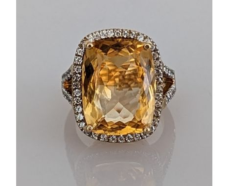 A citrine dress ring on a yellow gold split shank setting surrounded by cubic zirconia decoration, the cushion-cut faceted ci