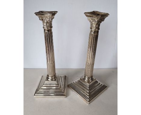 A pair of George V silver corinthian candlesticks with removable sconces, fluted columns on stepped, beaded square bases, hal