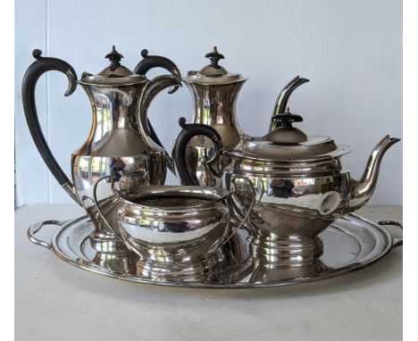A mid-century four-piece silver tea and coffee service (creamer missing) with ebonised handles on a matching two-handled oval