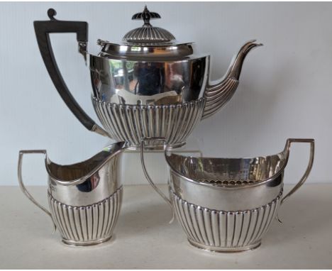 An Edwardian silver three-piece tea service with half fluted embossed design, ebonised knop and handle, hallmarked for Charle