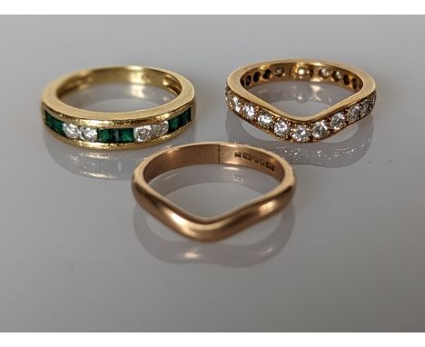 An emerald and diamond channel-set ring on a tapering shank; a wishbone diamond eternity ring and a wishbone band, all on 18c