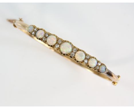 Early 20th C oval hinged gold bangle, set with seven graduated round cabochon cut opals and twelve old cut diamonds, conceale