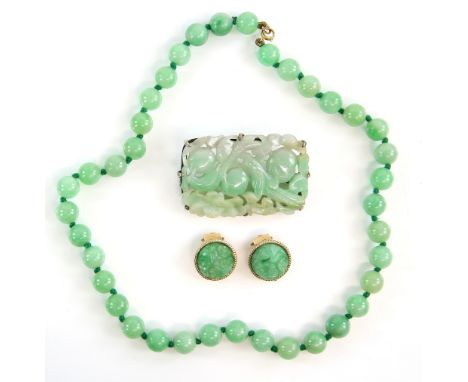 A  jade plaque brooch, carved as two birds among fruit and foliage, unmarked white metal mount, 3.8 x 5.2 cm, a jade bead nec