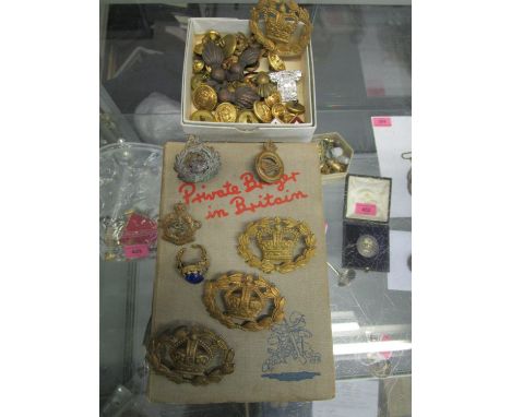 A selection of military cap badges, buttons and other items, along with a book 'Private Breger in Britain' with cartoons by D