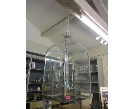 A large modern six branch ceiling hanging light having four glass panels and suspended by a chain 28"H x 14" wide (excluding 