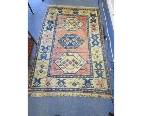 A Middle Eastern handwoven rug, geometric devices on a light red ground, triple guard border and tasselled ends 76" x 49 3/4"