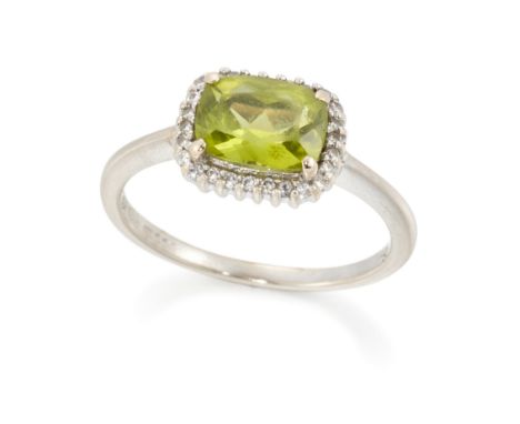An 18ct white gold peridot and diamond ring, of cluster design, with a cushion cut peridot and brilliant cut diamonds, London