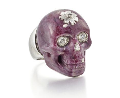 Theo Fennell. An 18ct white gold carved ruby and diamond skull ring, the realistically modelled skull of caved ruby with a br