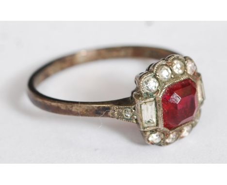 A silver and ruby garnet stone ladies dress ring. Central cushion cut ruby garnet with baguette stones and round cut stones t