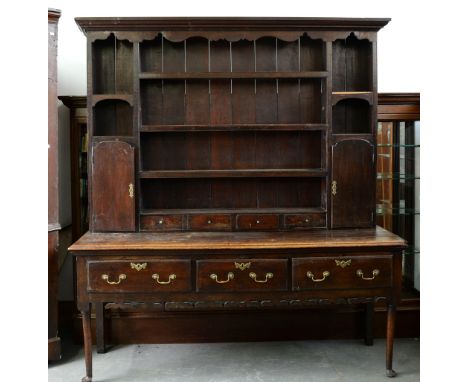A George III oak dresser, the later boarded rack with twin spice cupboards and drawers, the lower part with three moulded dra