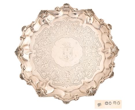 A Victorian silver waiter, engraved with armorials in strapwork surround, the border with shells at intervals, on four feet, 