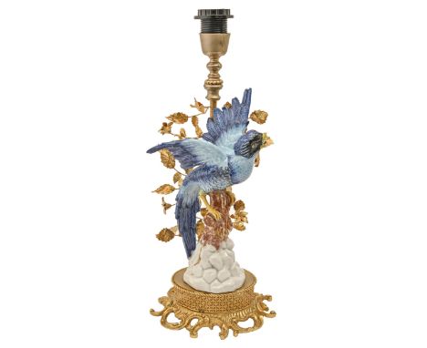 A Continental giltmetal and porcelain lamp, in the form of a bird on a stump before foliage, 39cm h excluding lamp holder  Go