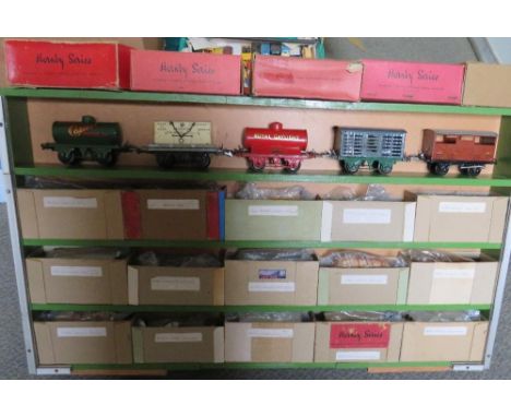 A WOODEN CABINET CONTAINING TWENTY PIECES OF O GAUGE ROLLING STOCK, to include tankers, cattle wagons, brake vans, side tippe