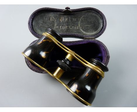 A CASED PAIR OF BRASS AND BELIEVED TORTOISESHELL OPERA GLASSES and the interior lid of the faux crocodile case bearing the na