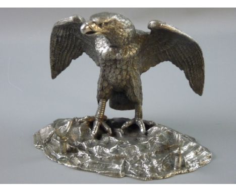 A WHITE METAL EAGLE DESK STAND, the bird with outstretched wings standing on a rocky base, the head hinged to reveal inkwell 