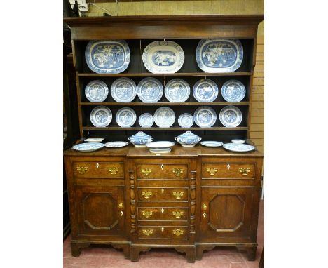 A NORTH WALES OAK BREAKFRONT DRESSER circa 1830 having a three shelf wide boarded rack over a planked top, three opening frie