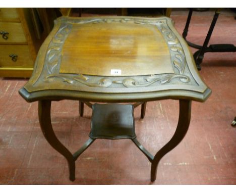 AN EDWARDIAN CARVED MAHOGANY SIDE TABLE, the shaped near square top with leaf decoration on swept supports with under tier sh