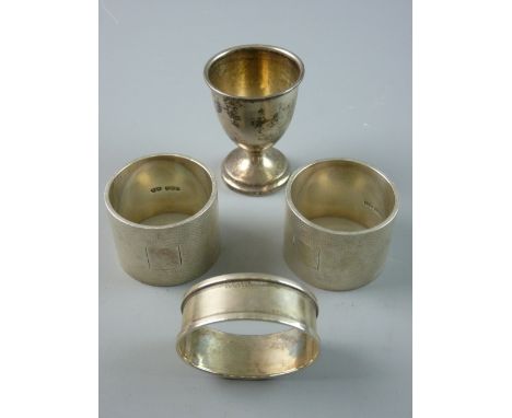 A PAIR OF VERY HEAVY ENGINE TURNED WIDE SILVER NAPKIN RINGS, 6 ozs, Birmingham 1913 and a silver eggcup and plain oval napkin