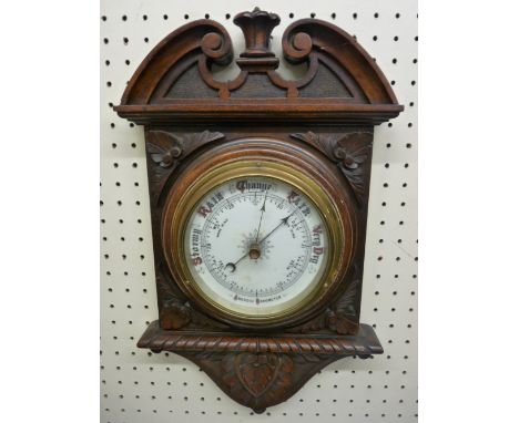 A VINTAGE OAK WALL MOUNTED ANEROID BAROMETER with porcelain dial and classically carved frame, 40 x 24 cms (repaired break to