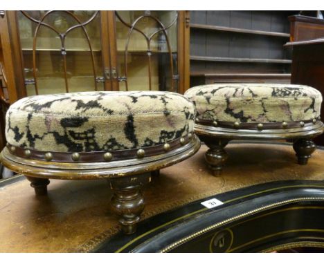 A PAIR OF CIRCULAR VINTAGE FOOTSTOOLS having upholstered tops with brass button edging on turned bun feet, 32 cms diameter