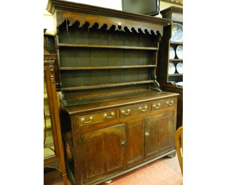 A MID 18th CENTURY WELSH OAK DRESSER, the three shelf wide boarded rack with inverted cornice over a decorative apron with ce