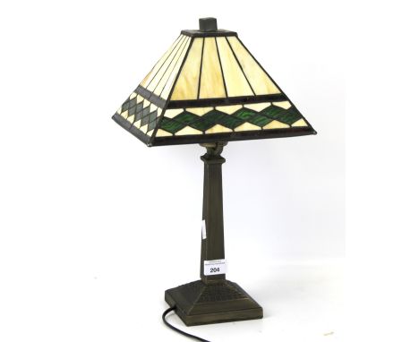 A contemporary Tiffany style lamp. The leaded shade with green glass details, mounted on a metal base with square support, H4