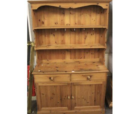 A modern pine kitchen dresser. With two shelves, one with cup hooks, above two frieze drawers above twin panelled doors enclo