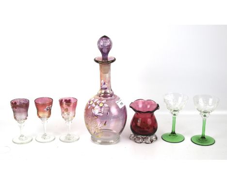 An assortment of glassware. Comprising a floral decanter with three matching glasses, a cranberry vase and two green stem vas