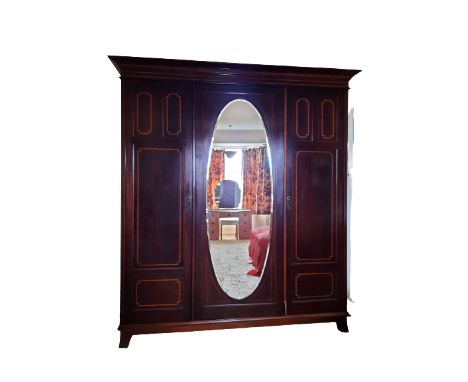 CIRCA 1900 INLAID MAHOGANY TRIPLE WARDROBE having central oval mirrored door and flanking boxwood inlaid four panel doors wit