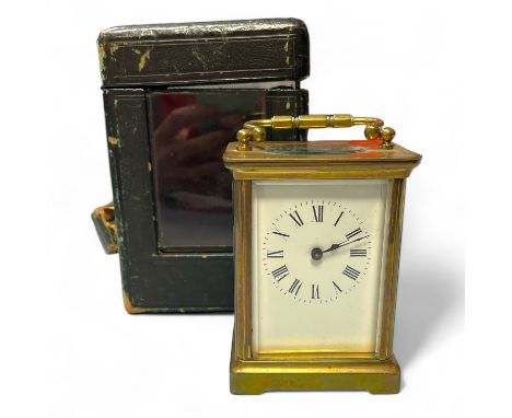 A brass carriage clock, 12cm tall with handle down in an associated leather case, in running order.&nbsp;