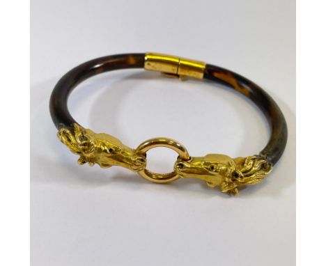 A high grade yellow gold double horsehead Tortoiseshell hinged bangle. One side of the bangle is at fault due to break in the