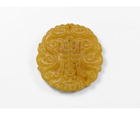 20th century AD. A carved discoid jade-like stone plaque with bifacial design of a central character flanked by dragons with 