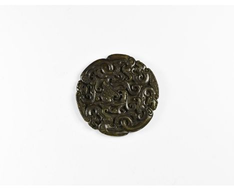 20th century AD. A carved discoid jade-like stone plaque with high-relief fenghuang bird amid a dense field of scrolled tendr