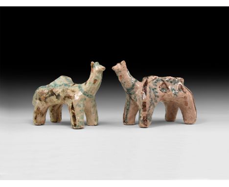 A pair of undated archaistic glazed ceramic animal figures each with a row of indented panniers to the sides, one with a cent